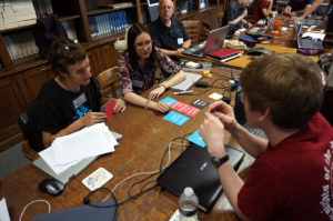 Young adults with visual impairments sitting around a table interacting with technology and paper cards as part of user testing