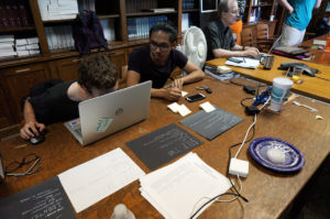 Young adults with visual impairments sitting around a table interacting with technology and paper cards as part of user testing