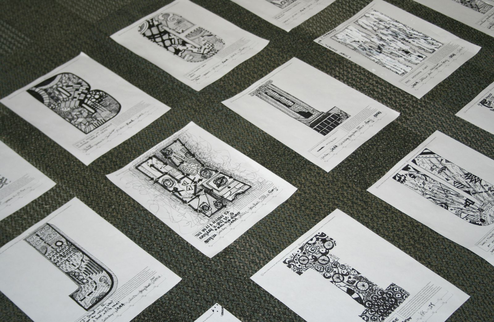 pages of hand-lettering lying on the floor. One letterform per page drawn in black ink